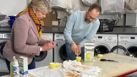Ökochecker-Host Tobias Koch befüllt unter Anleitung einer Expertin ein Waschei.