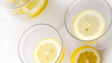 Mehrere Gläser Wasser mit einer Zitronenscheibe drin