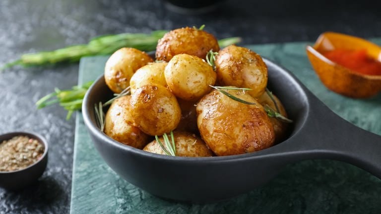 Bratpfanne mit gebackenen Kartoffeln und Rosmarin auf dunklem Hintergrund. (Foto: Adobe Stock, Adobe Stock/Pixel-Shot)