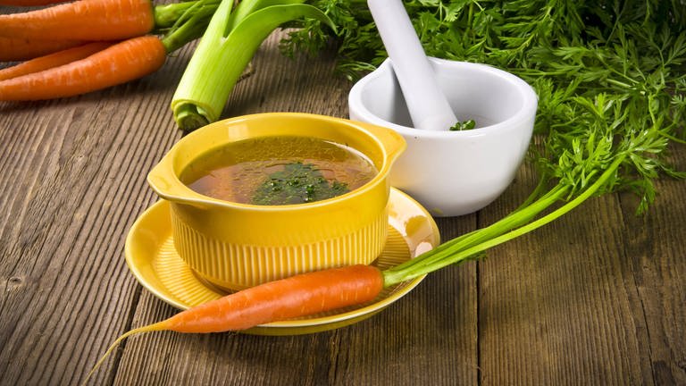 Eine Schale klare Gemüsebrühe mit Möhren. Klare Brühe aus Rind, Huhn, Fisch oder Gemüse ist die ideale geschmackliche Grundlage für Suppen.